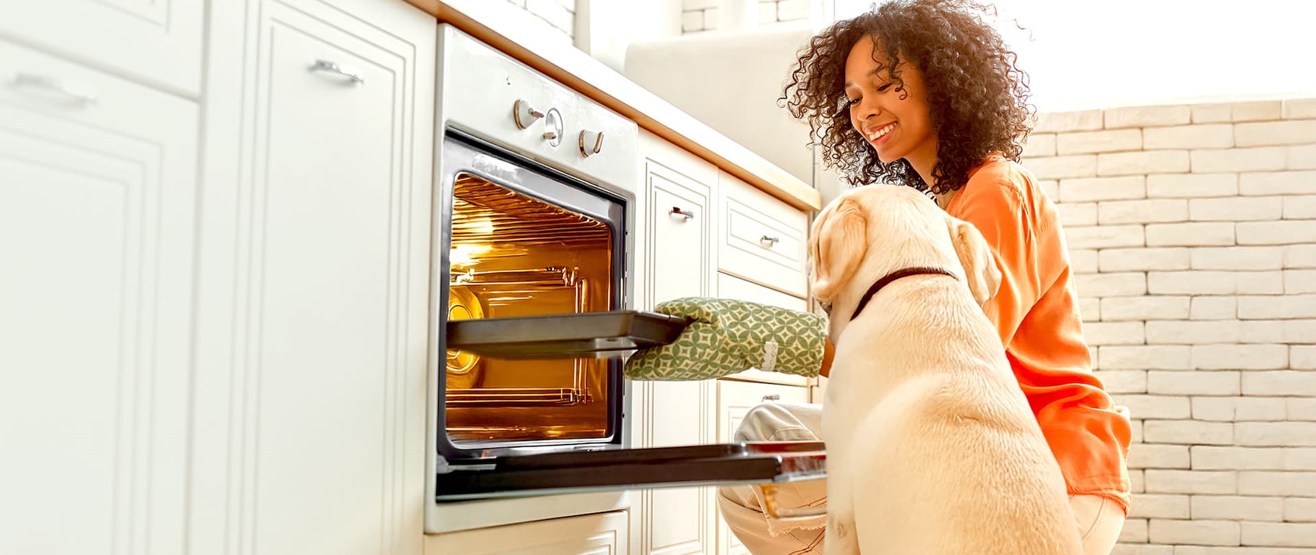 Hundekekse selber backen – gemeinsam mit deinem Hund in der Küche Frau backt Hundekekse in der Küche und wird dabei neugierig von ihrem Hund beobachtet